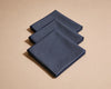 Three folded blue checkered hanky on a beige background