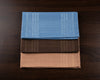 Three folded cotton hanky in blue, brown, and beige on a wooden surface