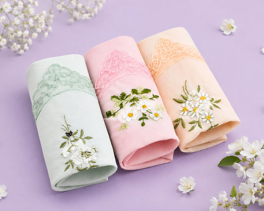 Three folded hanky with floral embroidery on a purple background