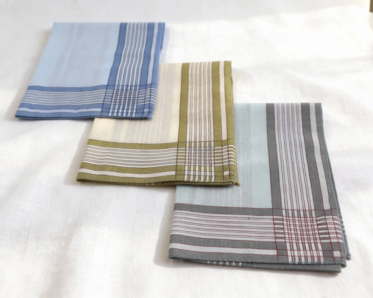 Three folded plaid hanky in blue, green, and gray on a white surface