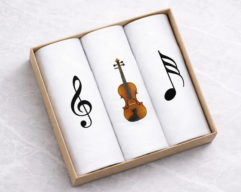 Three folded white hanky with musical design elements in a cardboard box on a light gray background