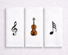Three hanky artworks featuring musical symbols and a violin on a white wall.