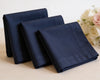 Three navy blue folded hanky on a light surface with flowers in the background