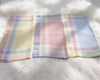 Three pastel plaid handkerchiefs on a white fur surface