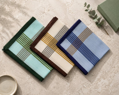 Three patterned hanky on a textured surface with a small plant.