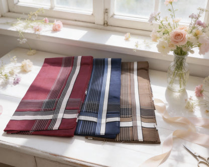 Three plaid scarves on a windowsill with flowers and ribbons.
