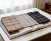 Three plaid fabrics on an open book with a blurred background