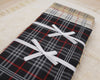Plaid fabric with white ribbons tied around on a textured surface