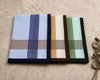 Three plaid handkerchiefs in different colors on a textured surface.
