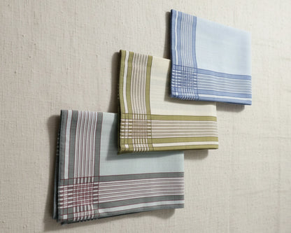 Three plaid handkerchiefs in different patterns on a textured beige background