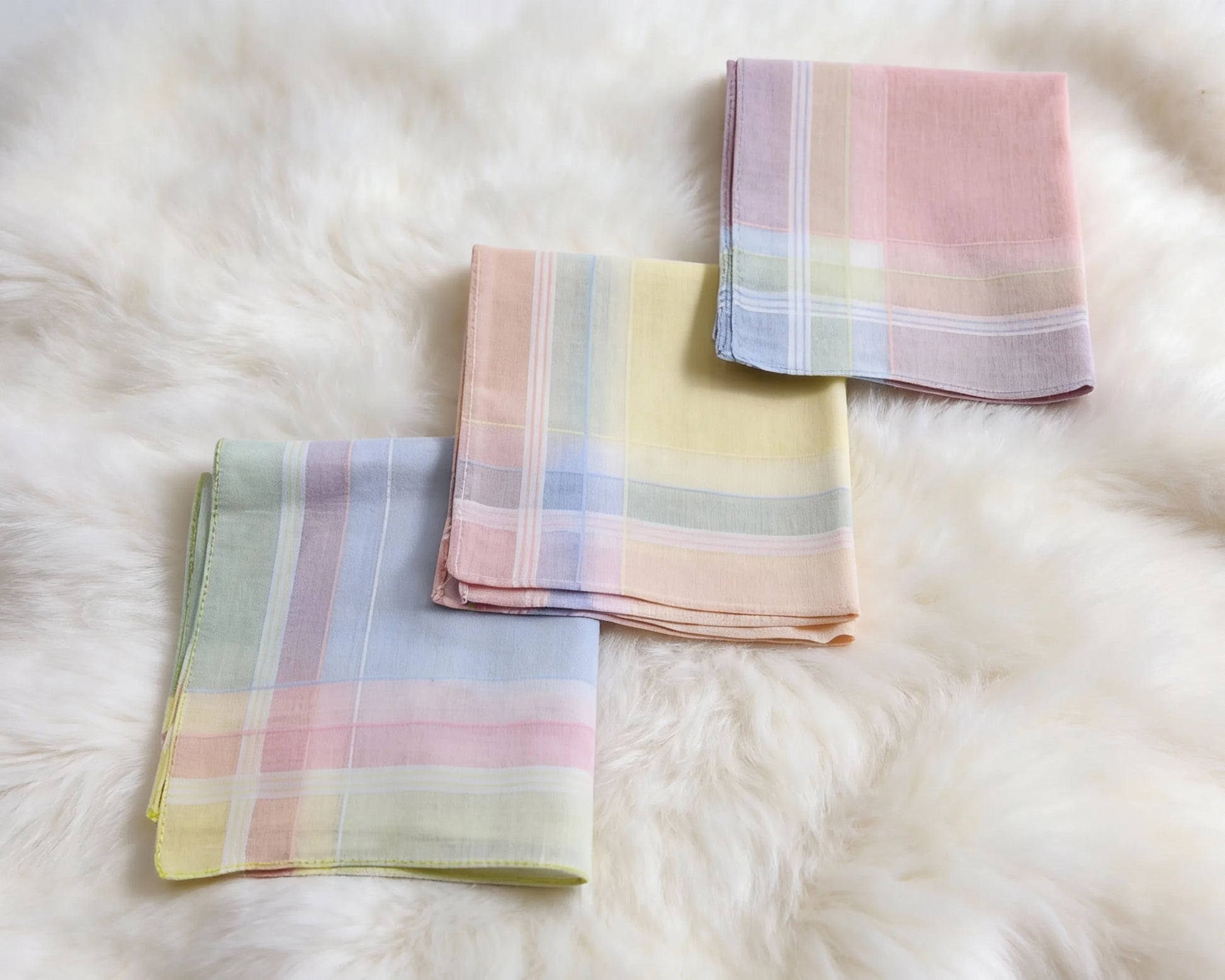 Three plaid hanky in pastel colors on a fluffy white surface