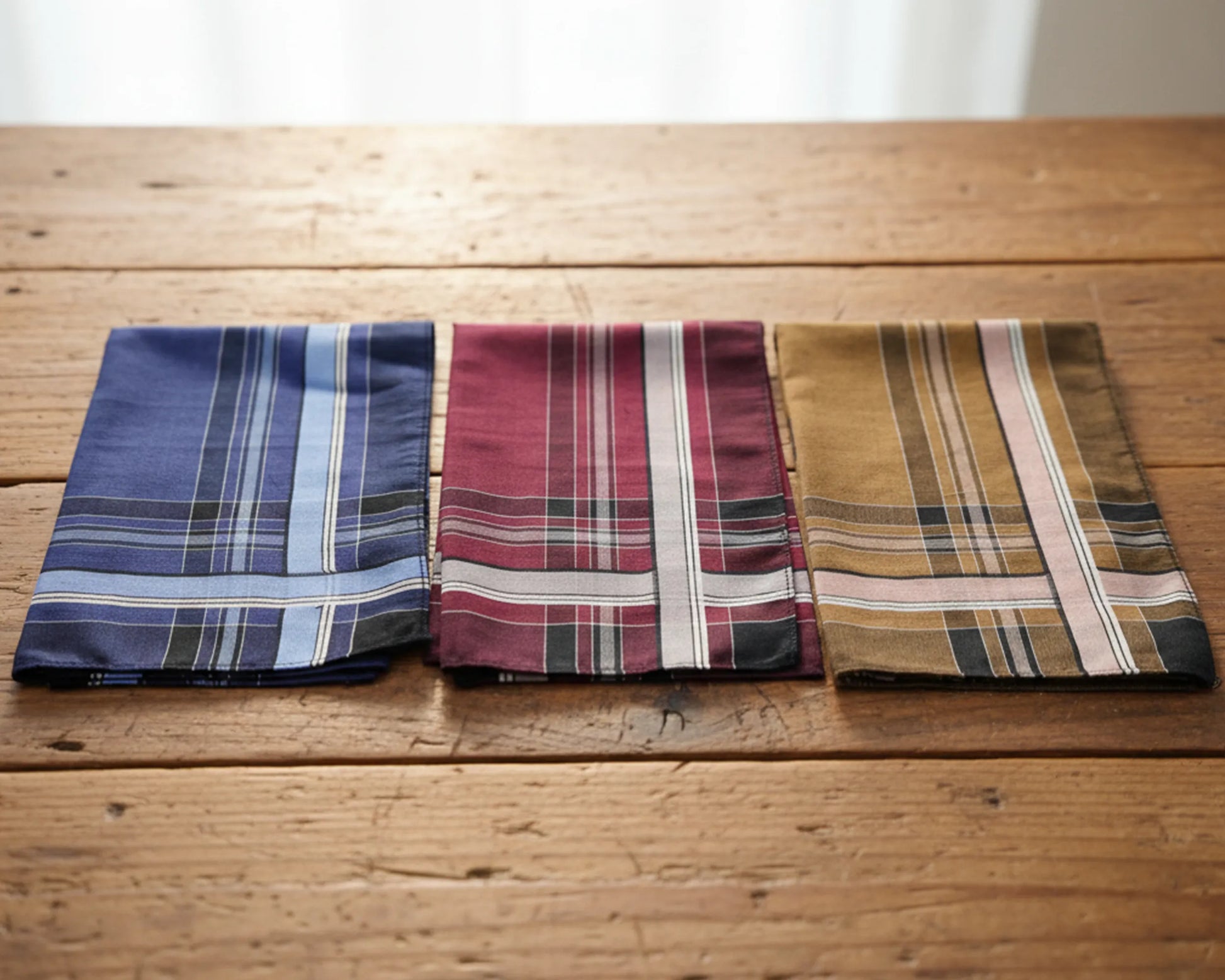 Three plaid pocket squares on a wooden surface