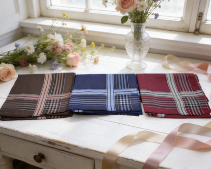 Three plaid pocket squares on a wooden surface with flowers in the background