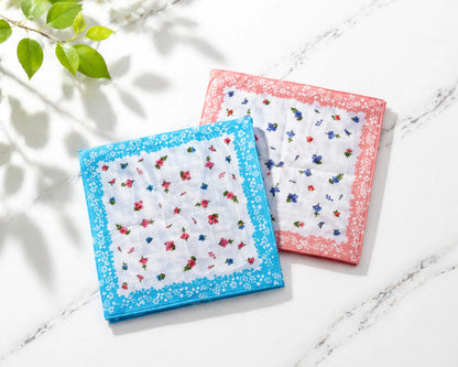 Two floral-patterned handkerchiefs on a light surface with a plant in the corner.