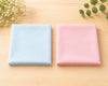 Two folded hanky, one blue and one pink, on a wooden surface with decorative elements.