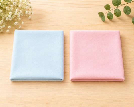 Two folded hanky, one blue and one pink, on a wooden surface with decorative elements.