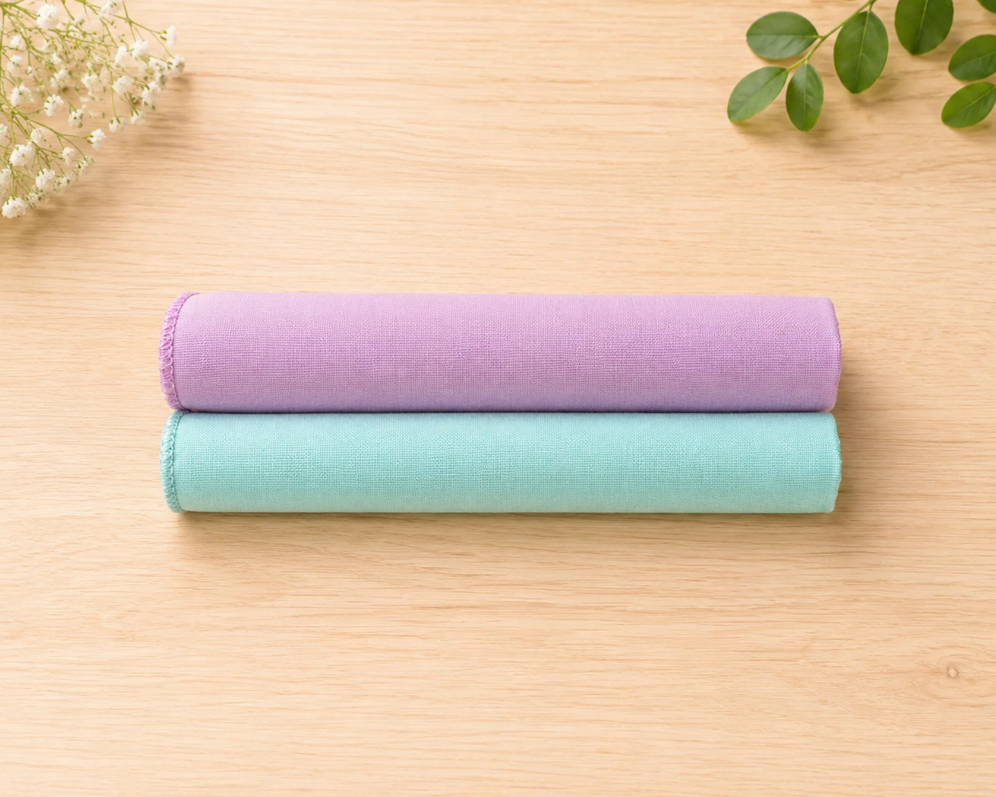 Two rolled-up hanky one purple and one green, on a wooden surface with a minimal background.