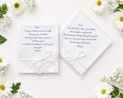 Two wedding handkerchief with heartfelt messages on a white surface surrounded by flowers