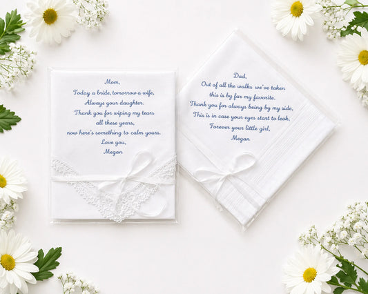 Two wedding handkerchief with heartfelt messages on a white surface surrounded by flowers