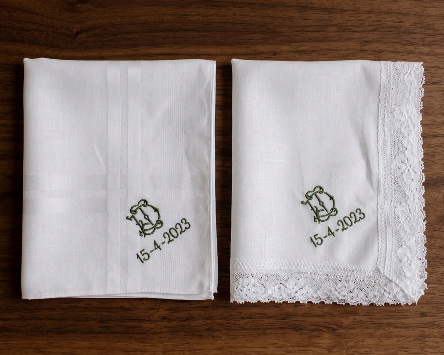 Two white handkerchiefs with embroidered designs and dates on a wooden surface