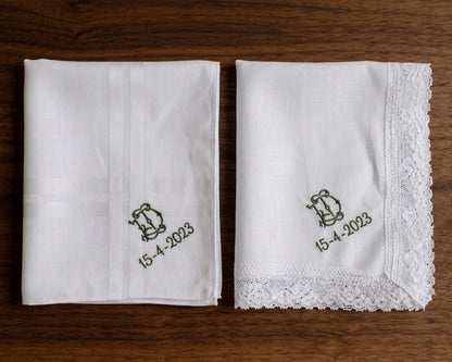Two white handkerchiefs with embroidered designs and dates on a wooden surface
