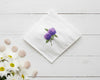 Detailed violet hydrangea embroidery with green leaves on a white cotton handkerchief displayed with smooth stones