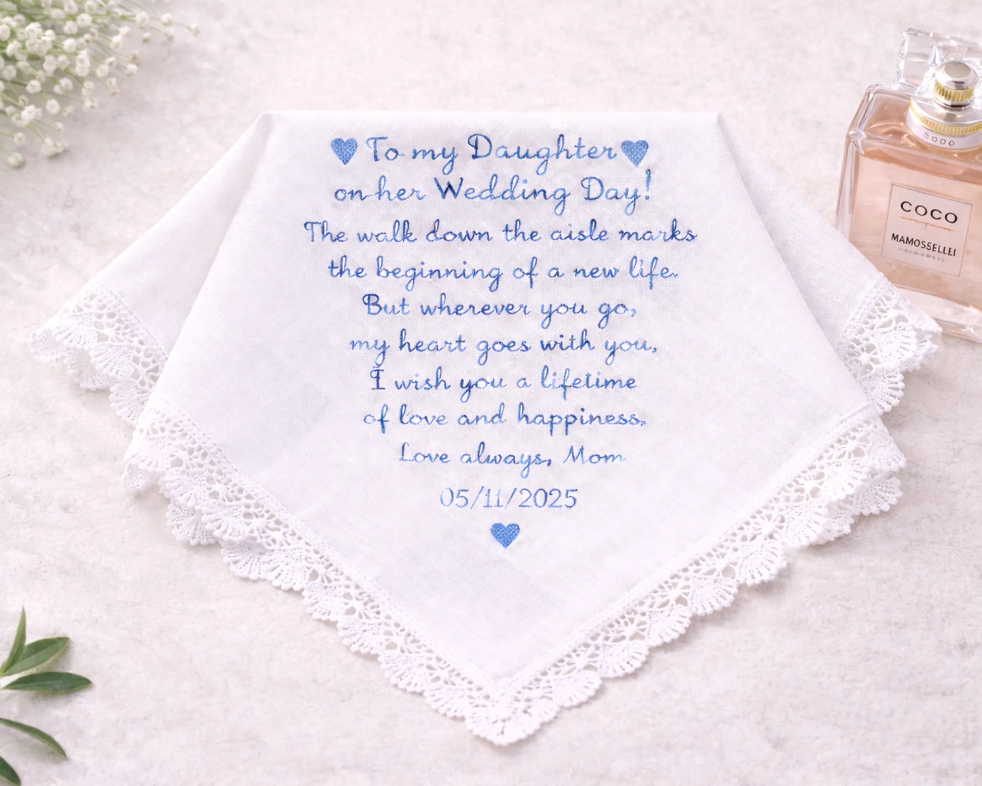Wedding handkerchief with personalized message and date, placed on a light surface with a bottle of perfume.