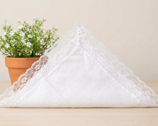 White lace-trimmed pillow on a beige surface with a potted plant in the background