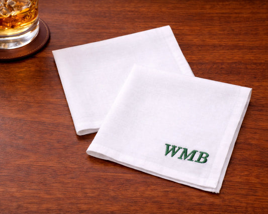 White embroidered hanky with design on a light surface with flowers around