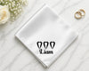 White handkerchief with 'Liam' and heart designs on a marble surface with flowers and rings.