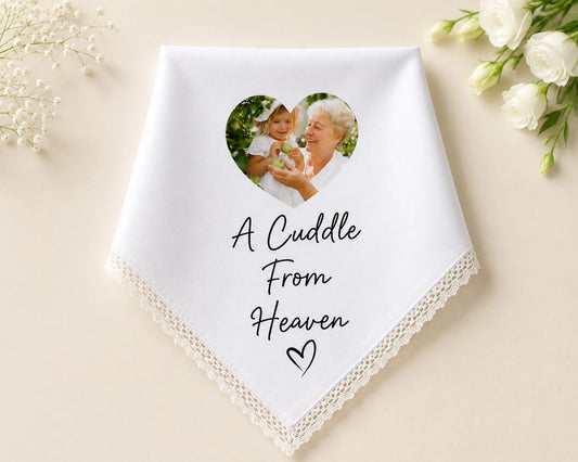 White handkerchief with a heart-shaped photo of a woman holding a baby and text 'A Cuddle From Heaven' on a beige background.