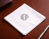 White handkerchief with a monogram on a brown leather surface