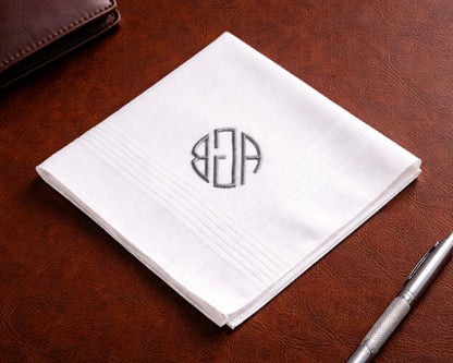 White handkerchief with a monogram on a brown leather surface