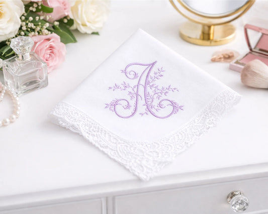 White handkerchief with a purple embroidered letter 'A' on a white surface with decorative items.