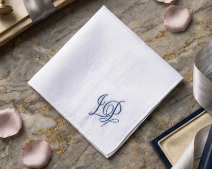 White handkerchief with blue monogram on a stone surface with decorative elements
