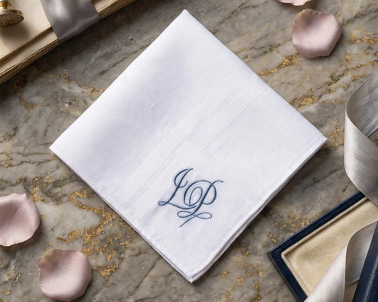 White handkerchief with blue monogram on a stone surface with decorative elements