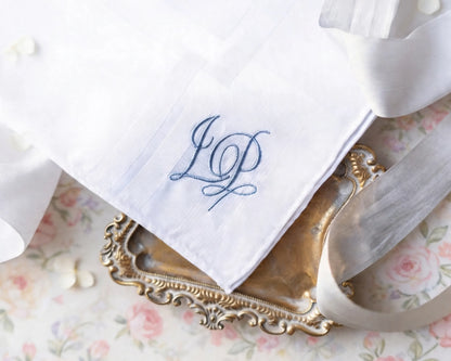 White handkerchief with blue monogram on a decorative tray with silverware