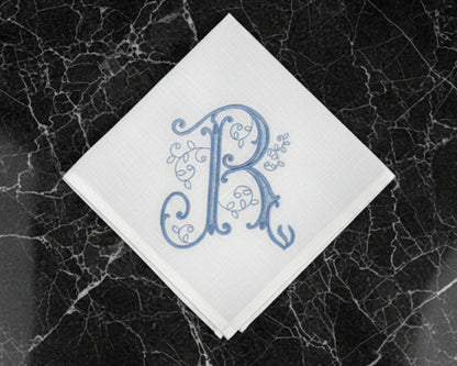White handkerchief with blue monogram 'R' on a black marble surface