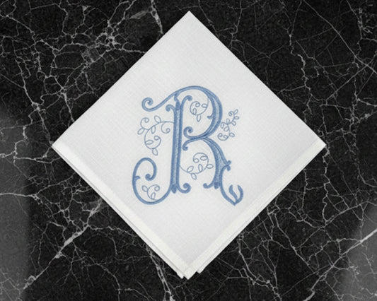 White handkerchief with blue monogram 'R' on a black marble surface