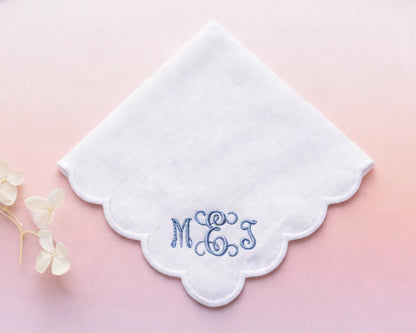 White handkerchief with embroidered initials 'MGS' on a pink background