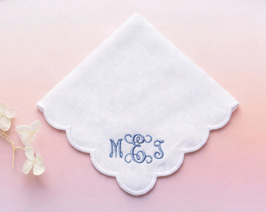 White handkerchief with embroidered initials 'MGS' on a pink background