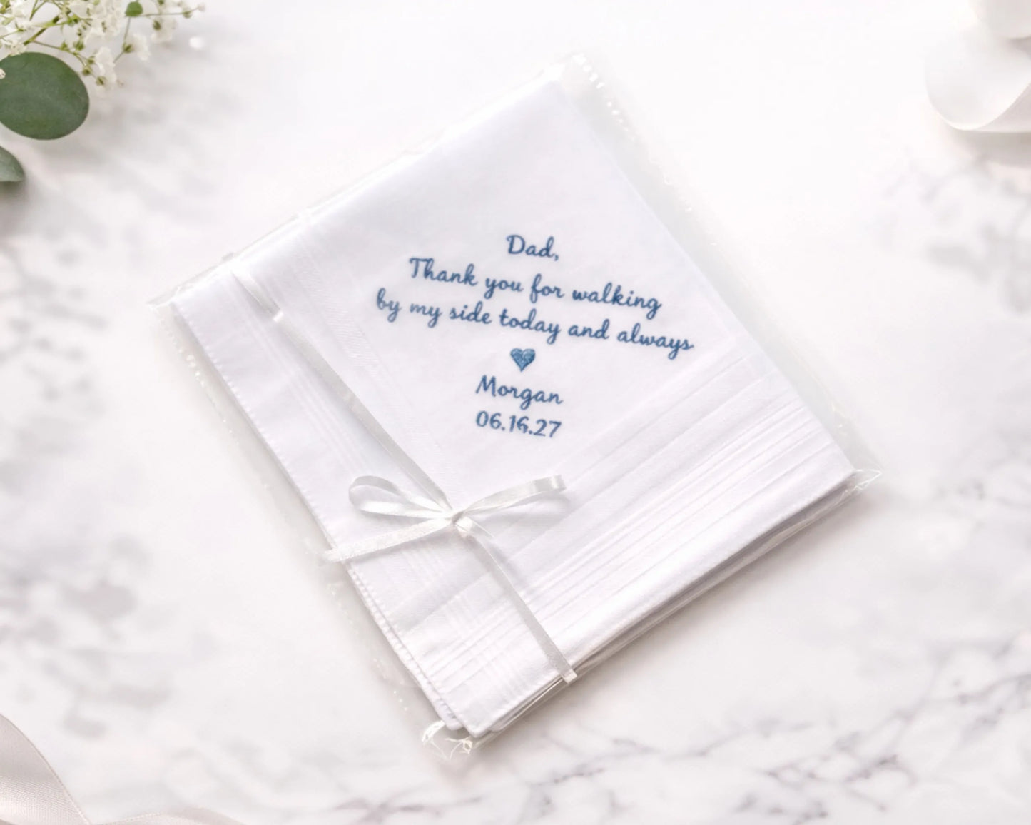 White handkerchief with embroidered message on a marble surface