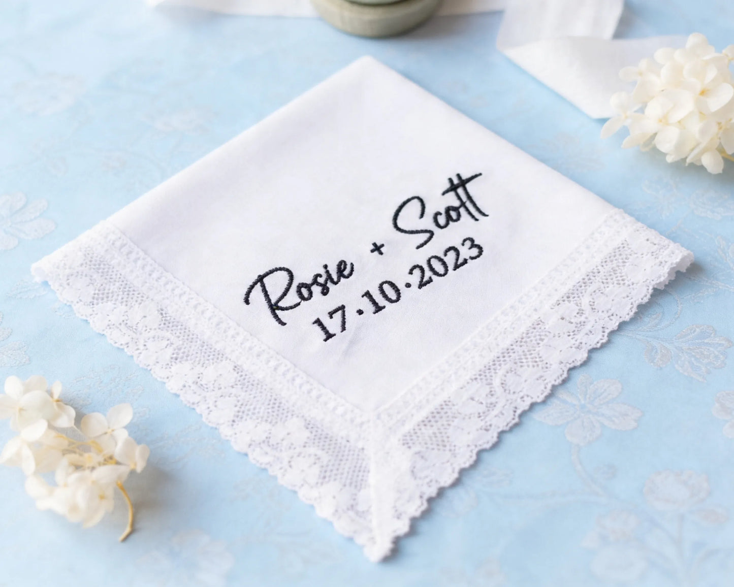 White handkerchief with embroidered text on a light blue background