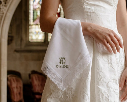 White handkerchief with lace details held by a person in a white dress, with '15-4-2023' printed on it, in an indoor setting.