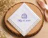 White handkerchief with purple monogram and date on a wooden coaster