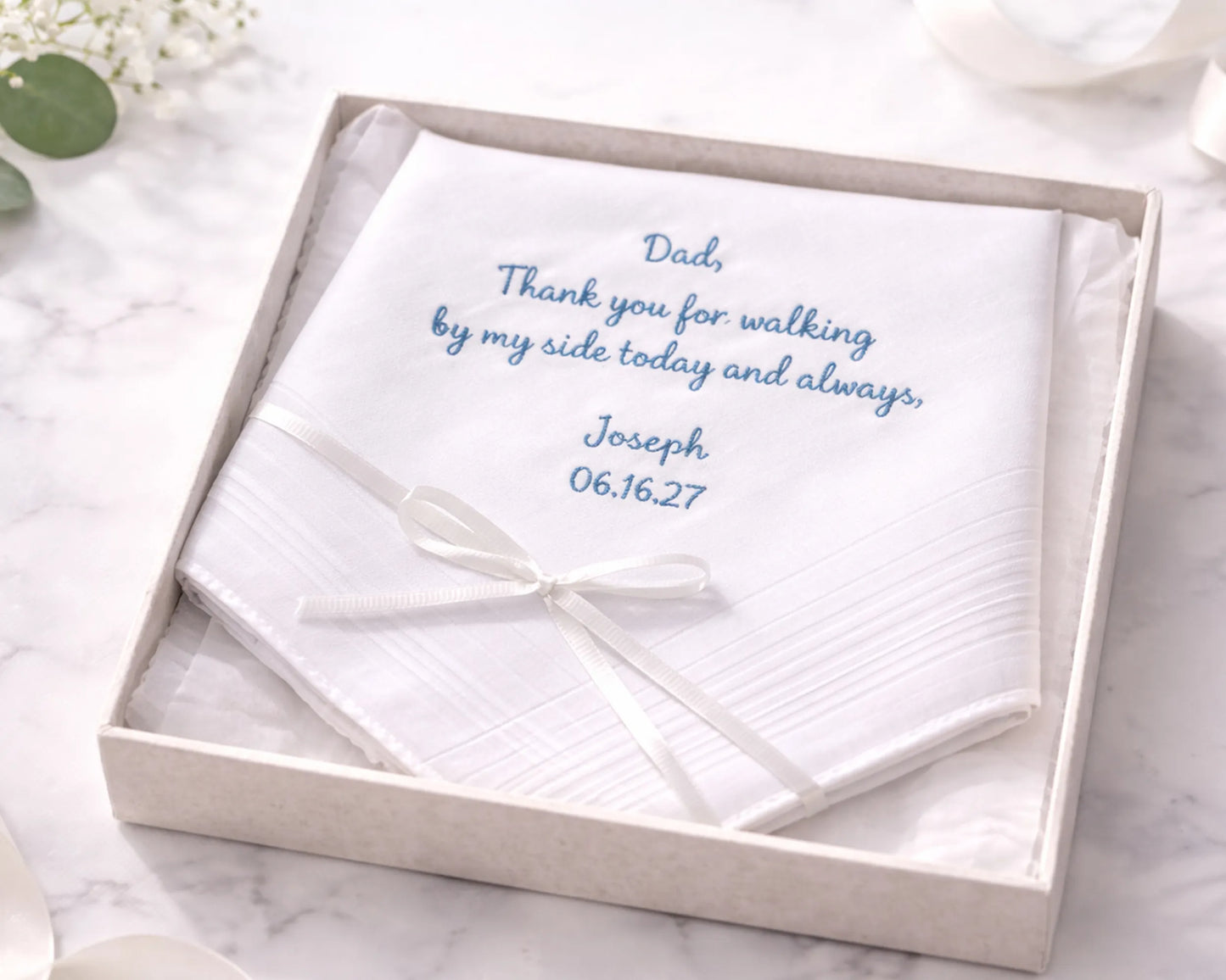 White handkerchief with personalized message in a box on a marble surface