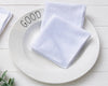 White hanky on a white plate with 'GOOD' text on a light wooden surface