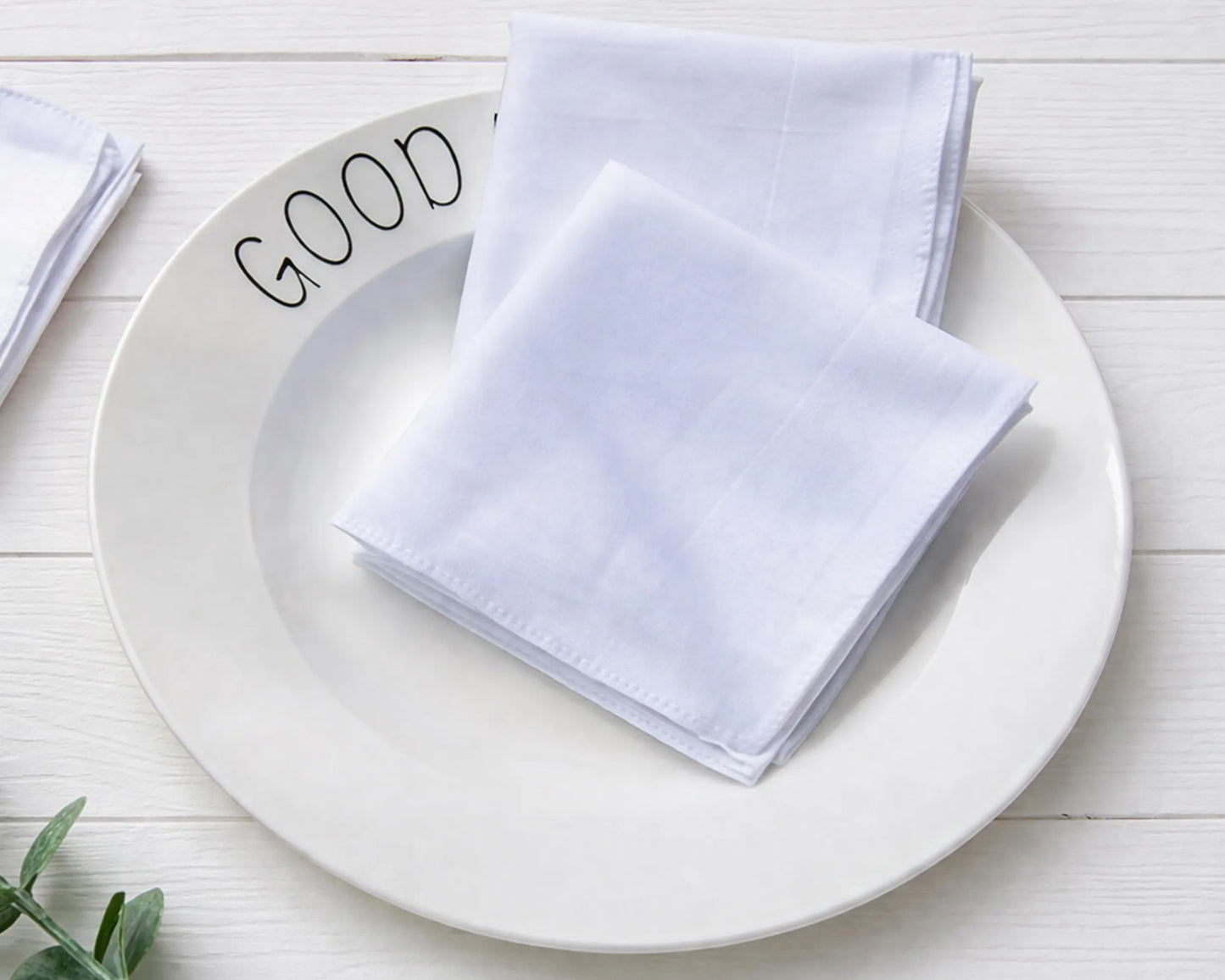 White hanky on a white plate with 'GOOD' text on a light wooden surface
