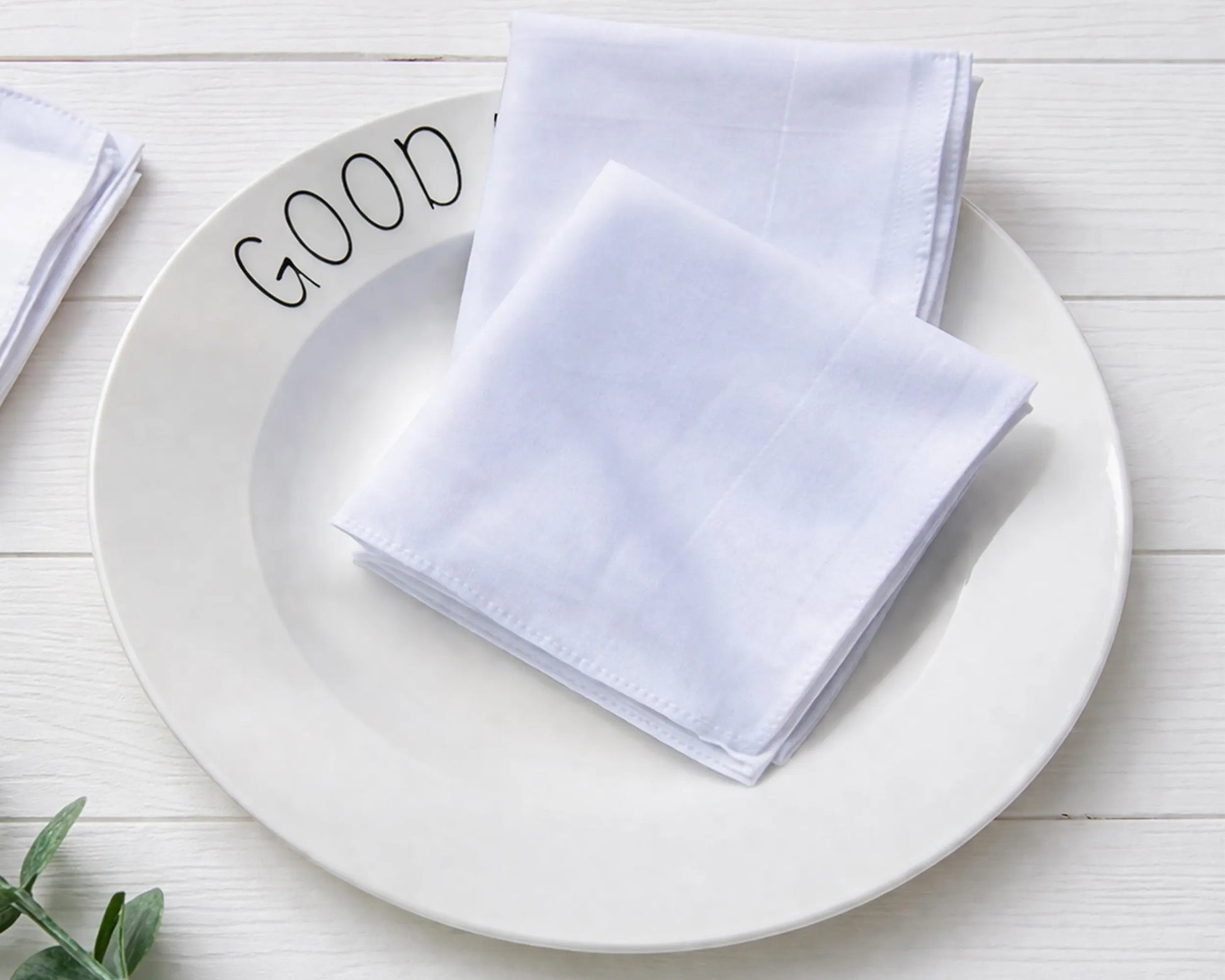 White hanky on a white plate with 'GOOD' text on a light wooden surface