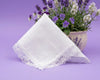 White lace-trimmed handkerchief on a purple background with a potted plant.